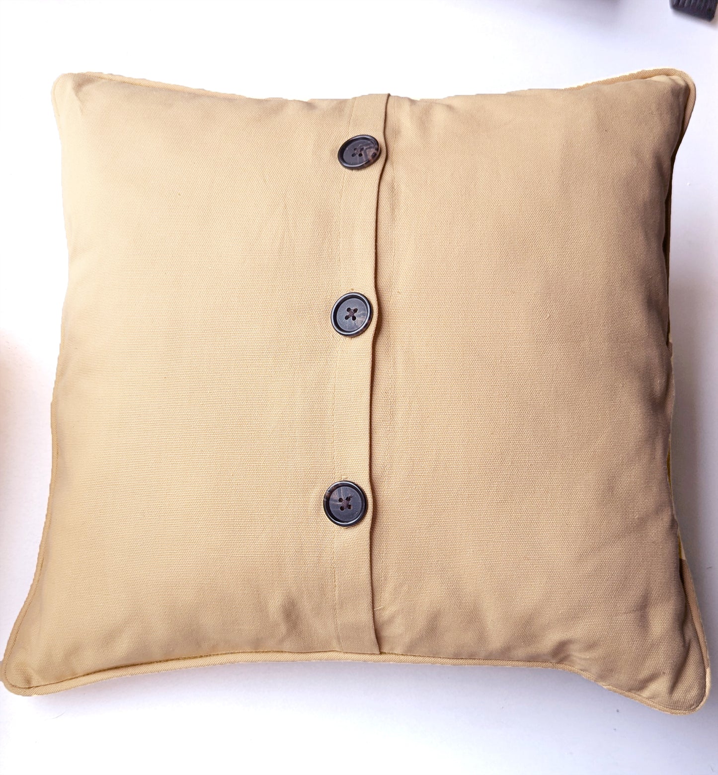 Beige pillow case with mermaid siren artwork on front and three black buttons on back running vertically.