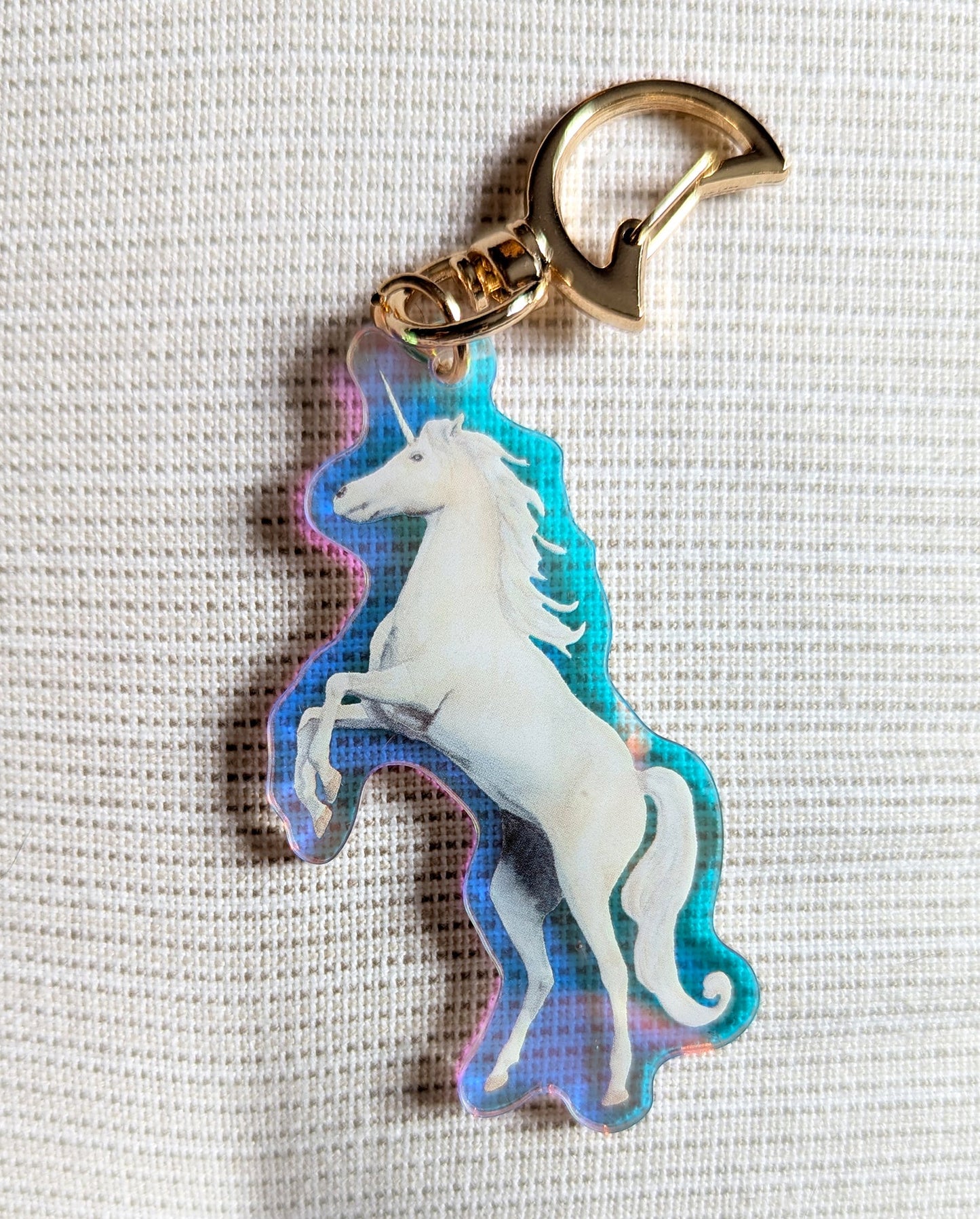 Two sided Unicorn keychain with iridescent rainbow effects and gold moon-shaped clasp. 