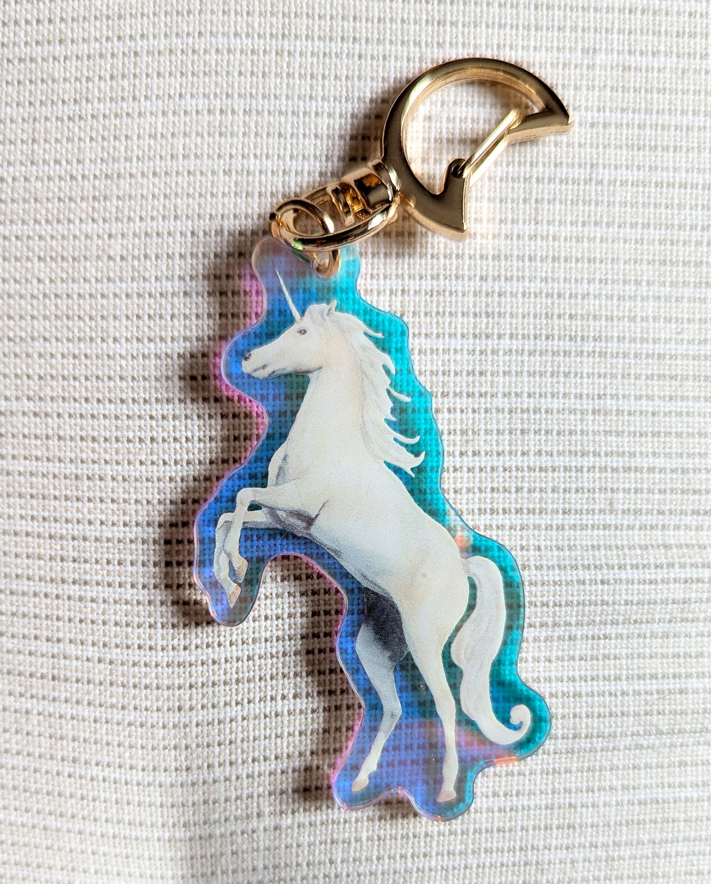 Two sided Unicorn keychain with iridescent rainbow effects and gold moon-shaped clasp. 